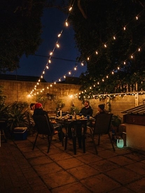 People dining al fresco outside underneath beautiful twinkling string lights from Stellar Lighting