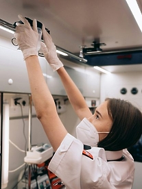 A female paramedic in an ambulance adjusting a drip while she treats a patient in an emergency service.