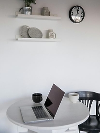 A Macbook on a white round table in a minimalistic home.